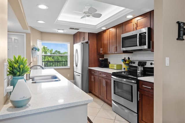 kitchen with backsplash, sink, ceiling fan, a raised ceiling, and stainless steel appliances