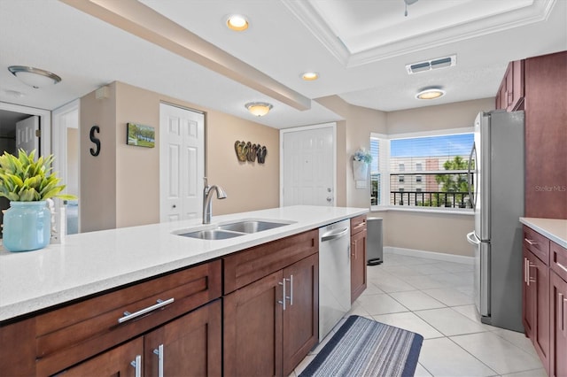 kitchen featuring sink, appliances with stainless steel finishes, a tray ceiling, and light tile patterned flooring