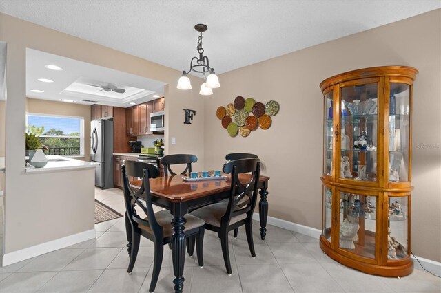 dining area with sink, light tile patterned flooring, a raised ceiling, and an inviting chandelier