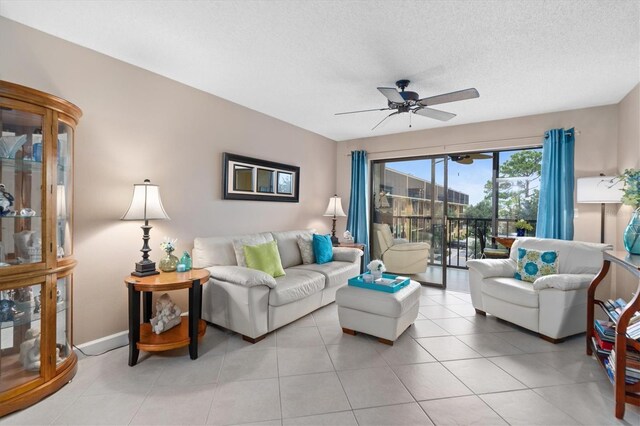 living room with ceiling fan, light tile patterned floors, and a textured ceiling