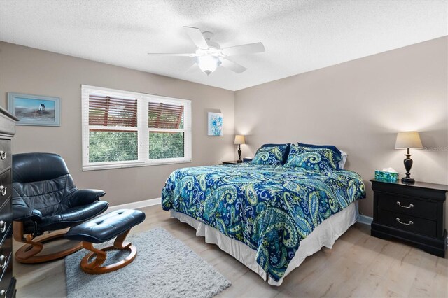 bedroom featuring ceiling fan, light wood-type flooring, and a textured ceiling