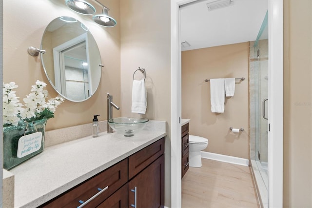 bathroom with a shower with door, vanity, and toilet