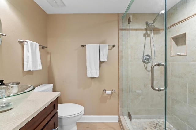 bathroom featuring a shower with door, vanity, and toilet