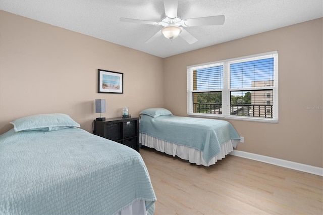 bedroom with a textured ceiling, light hardwood / wood-style flooring, and ceiling fan