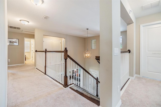 hallway featuring light carpet and an inviting chandelier