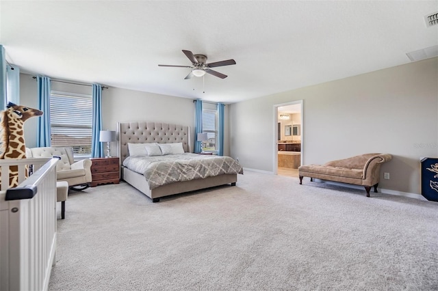 bedroom featuring ceiling fan, light colored carpet, and connected bathroom