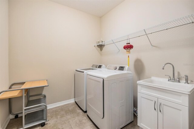 laundry room with sink, washer and clothes dryer, and cabinets