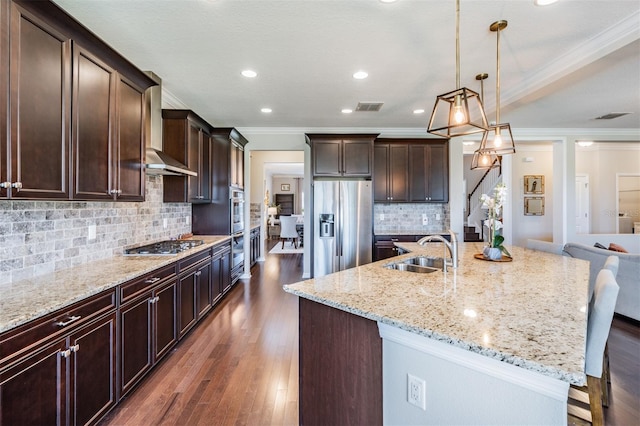 kitchen featuring a sink, a kitchen breakfast bar, dark wood finished floors, stainless steel appliances, and wall chimney exhaust hood