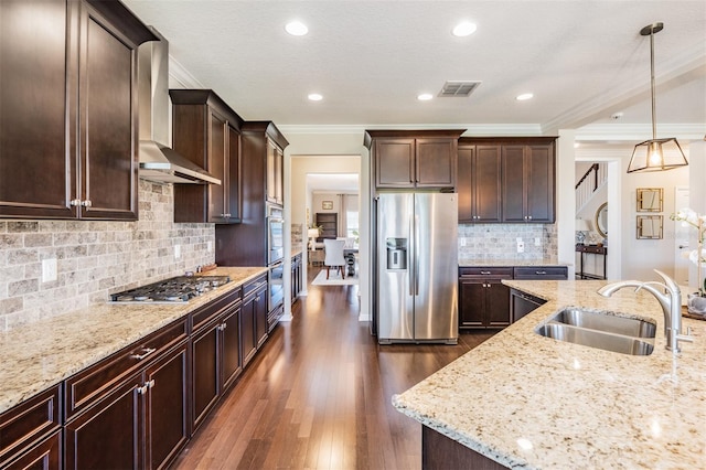 kitchen with visible vents, a sink, stainless steel appliances, wall chimney exhaust hood, and light stone countertops