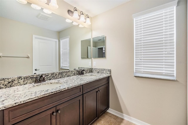 bathroom featuring a sink, baseboards, double vanity, and tile patterned flooring