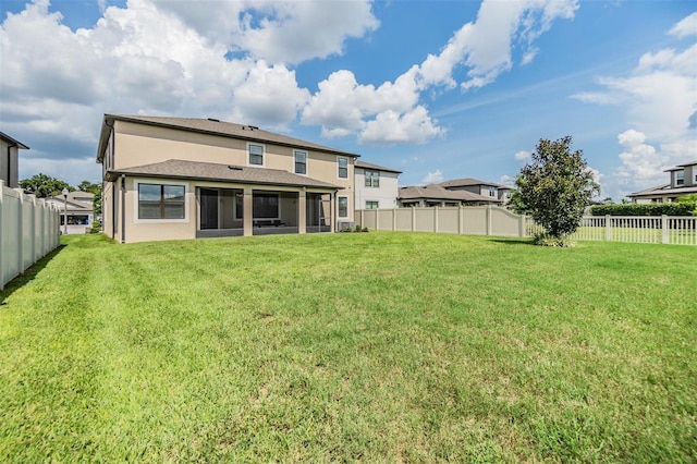 back of house with stucco siding, a lawn, a fenced backyard, and a sunroom