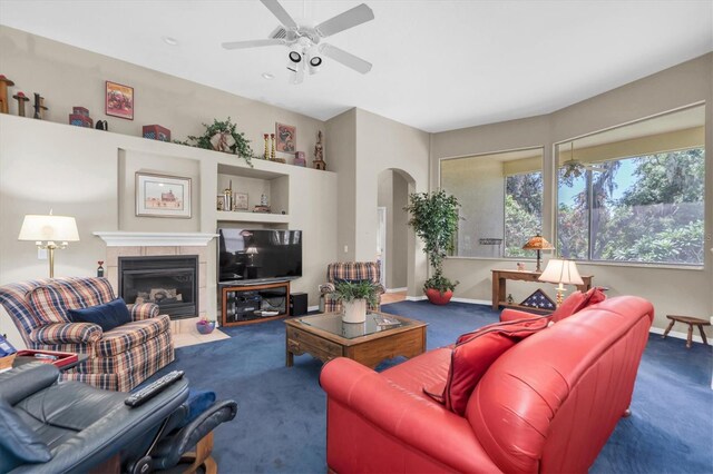 living room with built in features, a fireplace, carpet, and ceiling fan