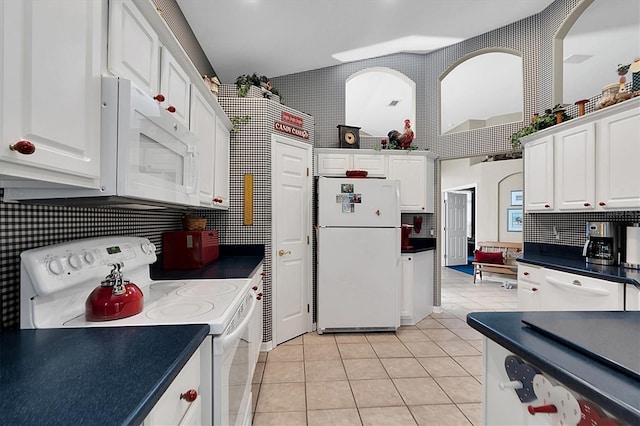 kitchen featuring white cabinetry, backsplash, light tile patterned flooring, and white appliances