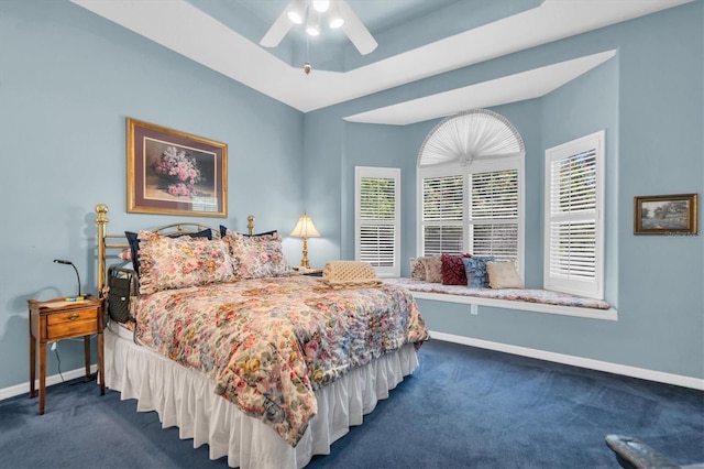 carpeted bedroom featuring ceiling fan and a raised ceiling