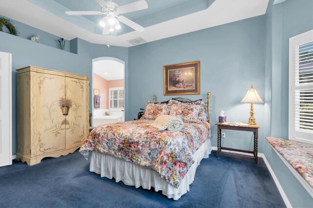 bedroom featuring carpet floors, connected bathroom, ceiling fan, and a tray ceiling