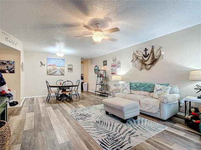 living room featuring ceiling fan, wood-type flooring, and a textured ceiling