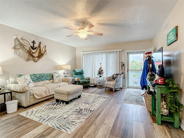 living room featuring ceiling fan, hardwood / wood-style floors, and a textured ceiling