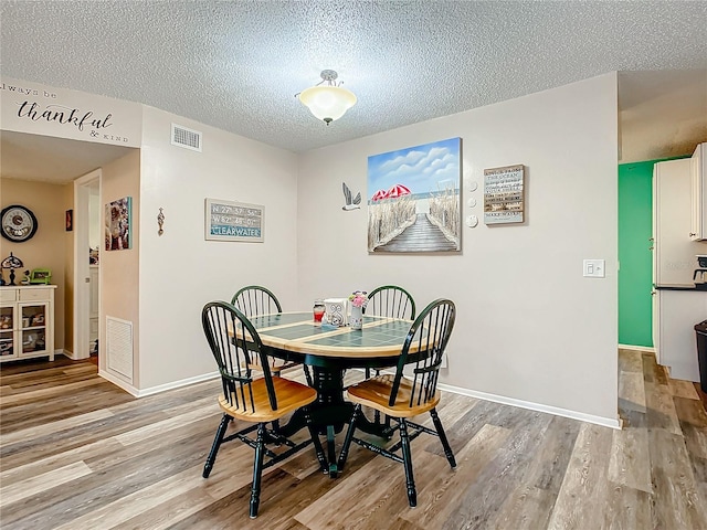 dining room with a textured ceiling and hardwood / wood-style floors