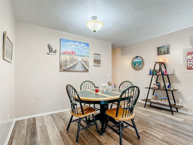 dining room with hardwood / wood-style flooring and a textured ceiling