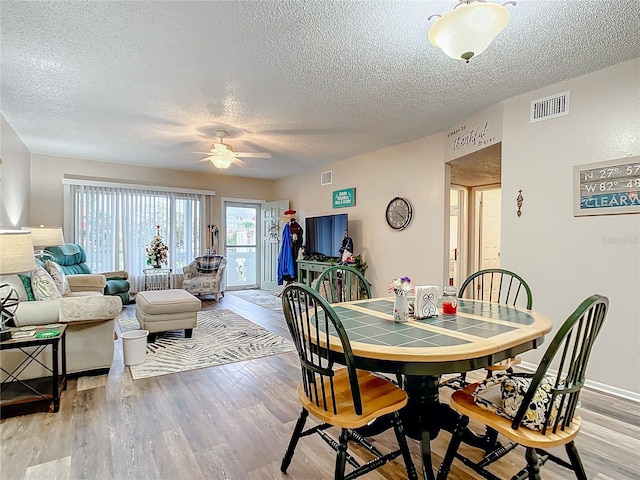 dining space featuring a textured ceiling, ceiling fan, and light hardwood / wood-style floors