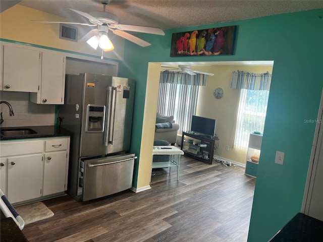 kitchen featuring white cabinetry, hardwood / wood-style flooring, stainless steel refrigerator with ice dispenser, sink, and backsplash