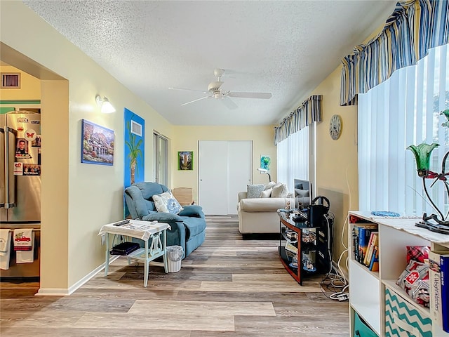 living room featuring a textured ceiling, ceiling fan, and light hardwood / wood-style floors