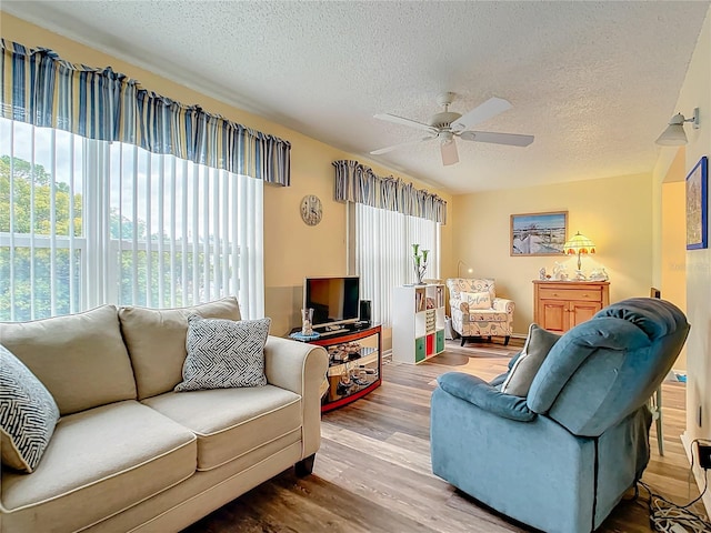 living room featuring wood-type flooring, a textured ceiling, and ceiling fan