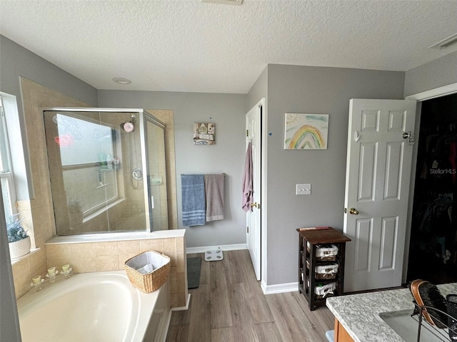 bathroom featuring shower with separate bathtub, wood-type flooring, and a textured ceiling