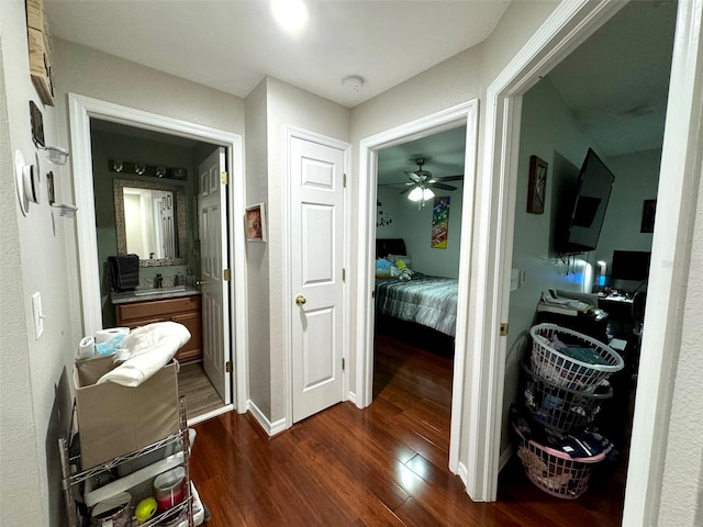 corridor with dark wood-type flooring and sink