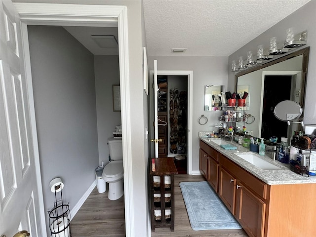 bathroom featuring double vanity, a textured ceiling, toilet, and hardwood / wood-style floors