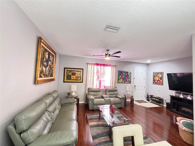 living room featuring ceiling fan, dark hardwood / wood-style flooring, and a textured ceiling