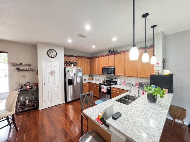 kitchen with appliances with stainless steel finishes, dark hardwood / wood-style flooring, sink, and hanging light fixtures