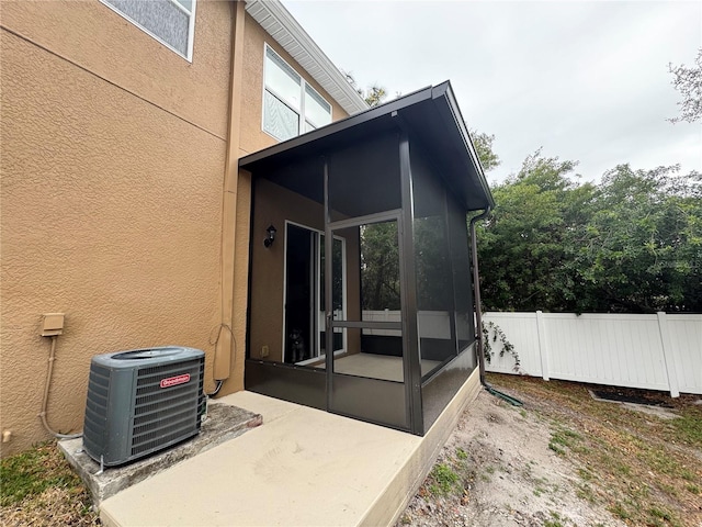 exterior space featuring a sunroom, a patio, and central air condition unit