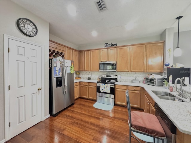6546 Marlberry Way, Largo, FL 33773 - kitchen featuring dark wood-style flooring, appliances with stainless steel finishes, a sink, backsplash, and visible vents