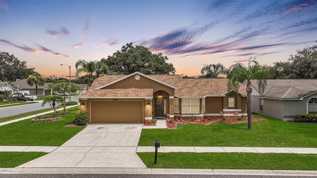 ranch-style home with a garage and a lawn