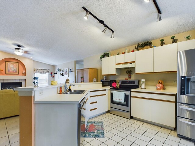 kitchen with a fireplace, appliances with stainless steel finishes, rail lighting, and a textured ceiling