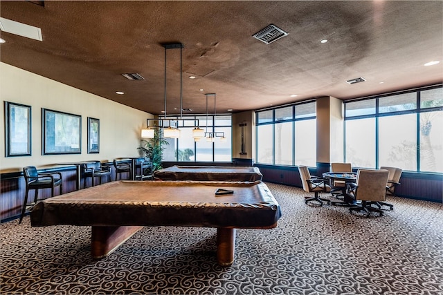 game room with carpet, visible vents, and a textured ceiling