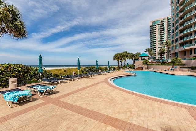 pool featuring a water view and a patio