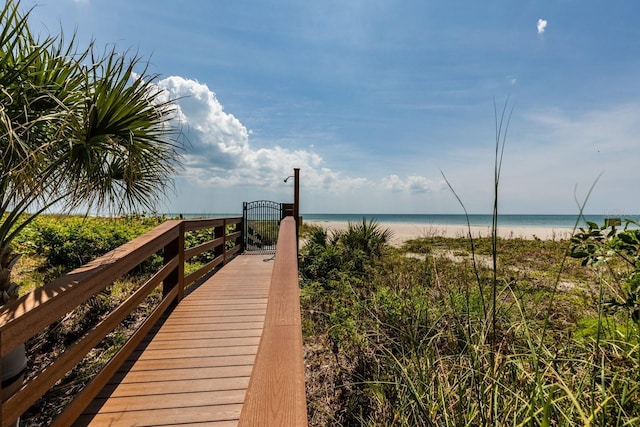 view of property's community with a view of the beach, a gate, and a water view