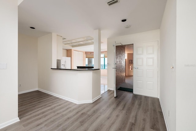 kitchen featuring baseboards, white fridge with ice dispenser, visible vents, and wood finished floors