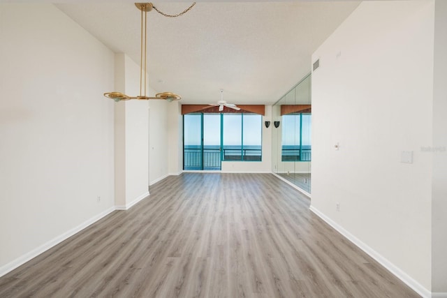 unfurnished living room featuring a textured ceiling, light wood finished floors, visible vents, and baseboards