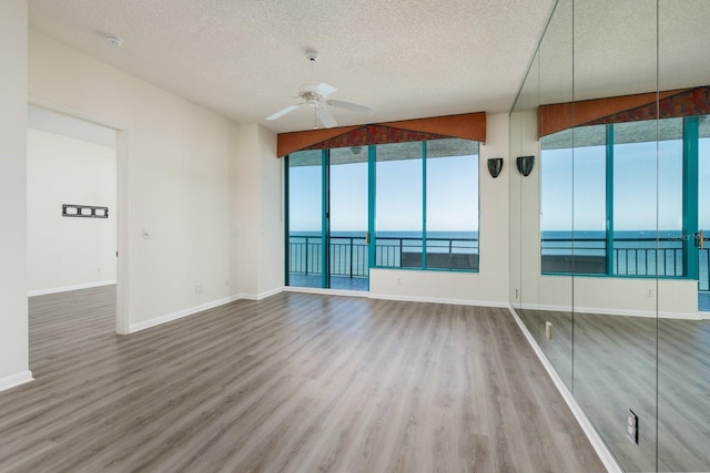 unfurnished room with ceiling fan, wood finished floors, and a wealth of natural light