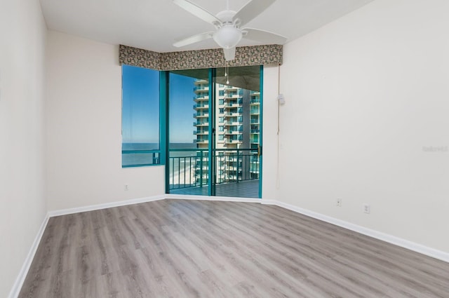 empty room with ceiling fan, baseboards, and wood finished floors