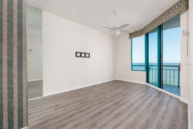 empty room featuring wood finished floors, a ceiling fan, and baseboards