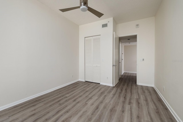 unfurnished bedroom with a closet, visible vents, baseboards, and wood finished floors