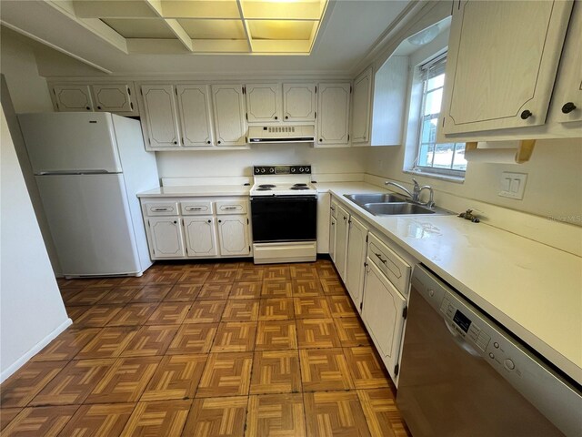 kitchen with sink, white appliances, dark parquet floors, and white cabinetry