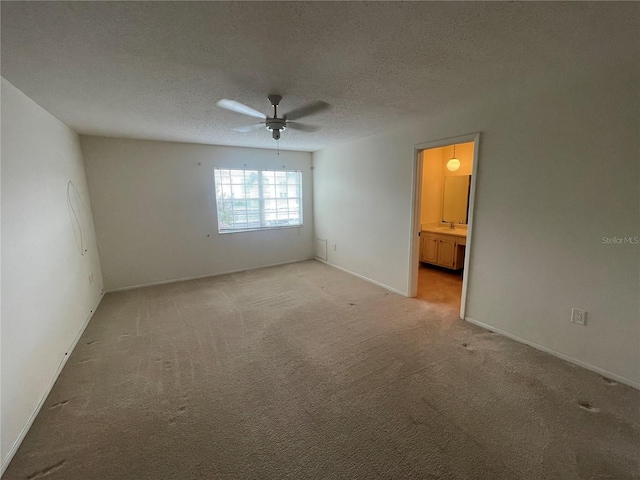 carpeted spare room with sink, a textured ceiling, and ceiling fan