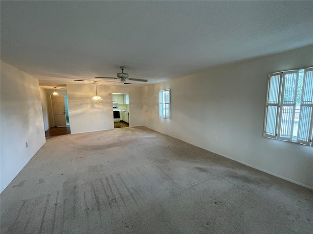 unfurnished living room with carpet and ceiling fan