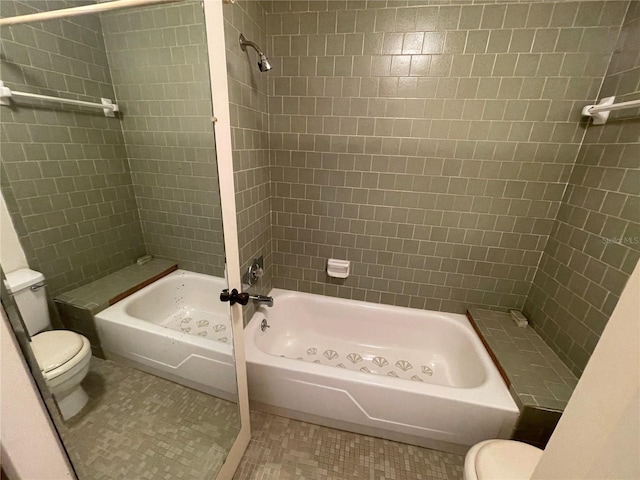 bathroom with tile patterned flooring, tiled shower / bath combo, and toilet