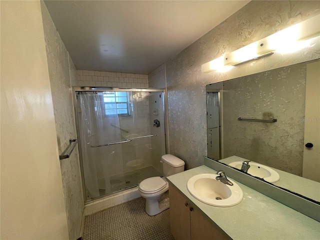 bathroom with tile patterned flooring, a shower with shower door, toilet, and vanity